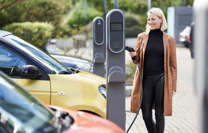 A photo of a young woman connecting her vehicle to an office car park EV charger