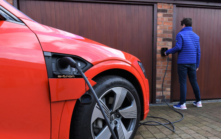A photo of a young man connecting his Audi e-tron to his EO home car charger